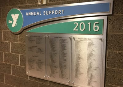 ADA interior sign on brick wall for the YMCA with donor names.