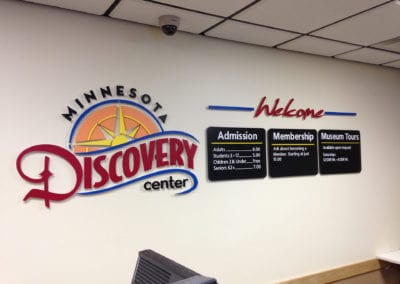 ADA interior sign for Minnesota Discovery Center showing logo, admission prices and membership details